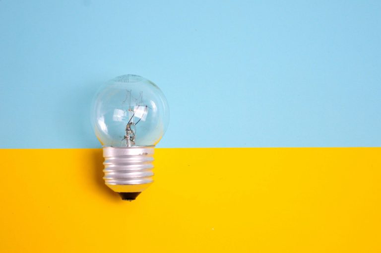 A clear light bulb on a blue and yellow background, representing energy savings
