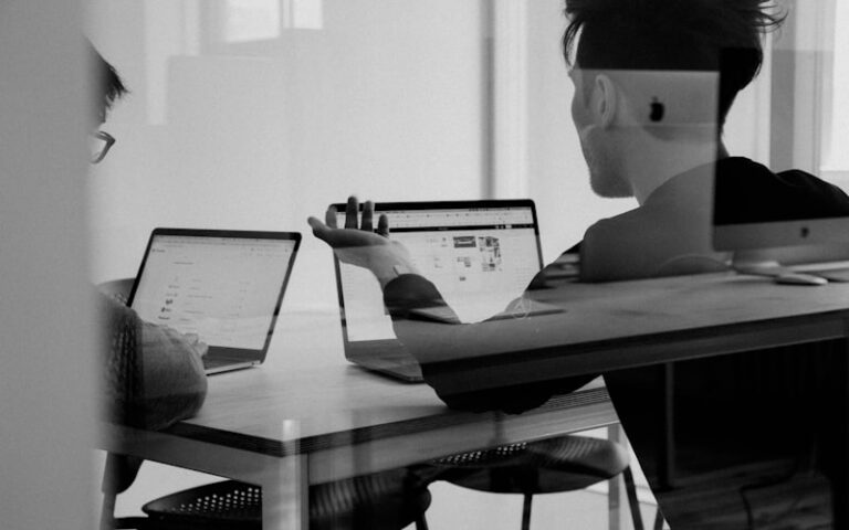 Two people working at laptops in an office