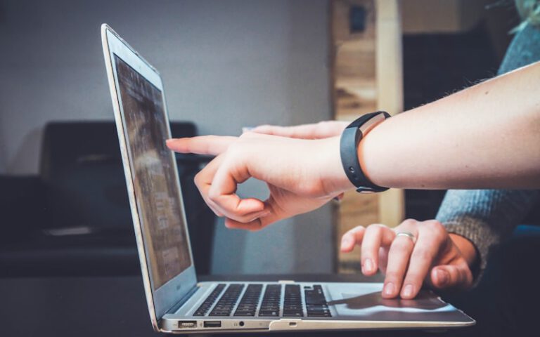 A person pointing at a laptop screen while another person types