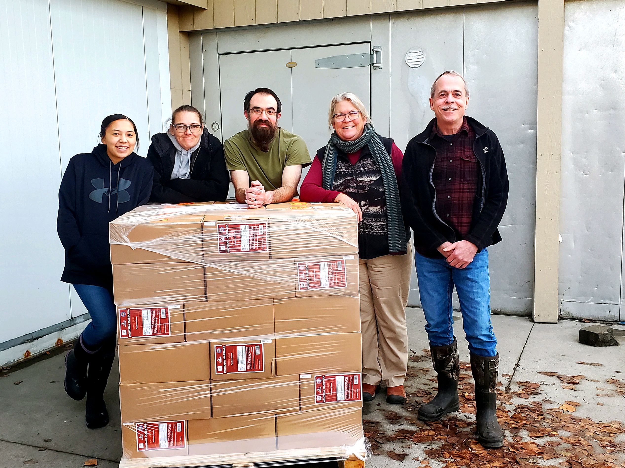 Mission West team beside a shrink-wrapped pallet of boxed Mission West Marinara ready to ship