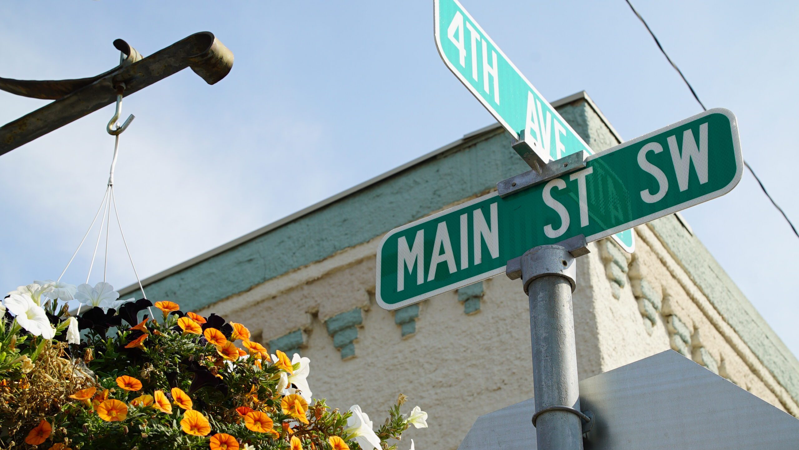 Main Street SW and 4th Avenue street signs with flower baskets in downtown Ronan, Montana