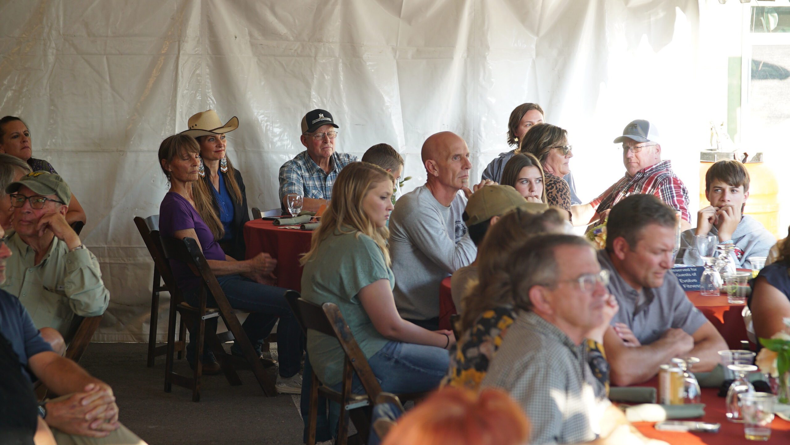 Guests seated under a tent listening during the Harvest on Main dinner