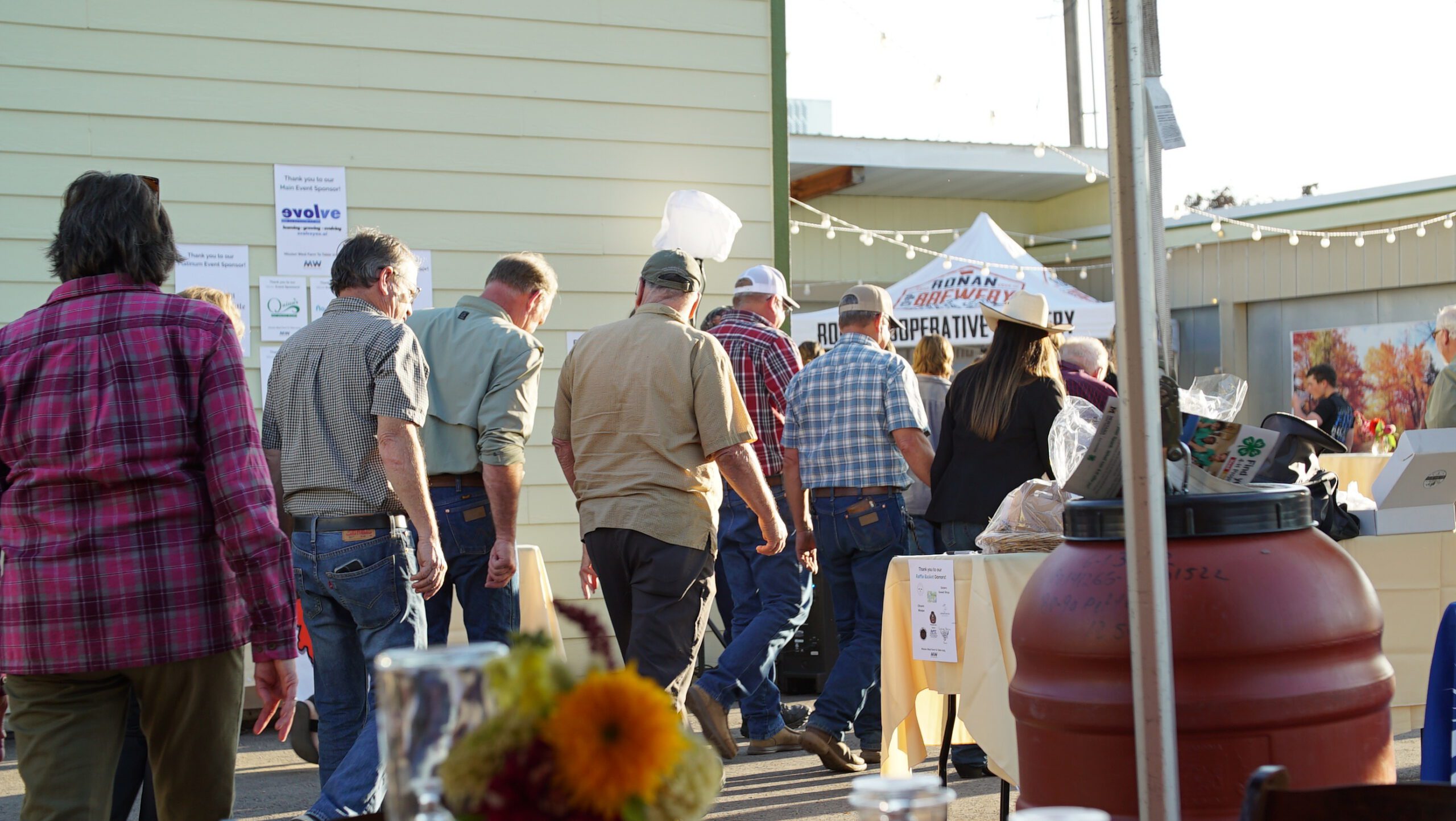 Community members gathering at an outdoor Mission West event at golden hour
