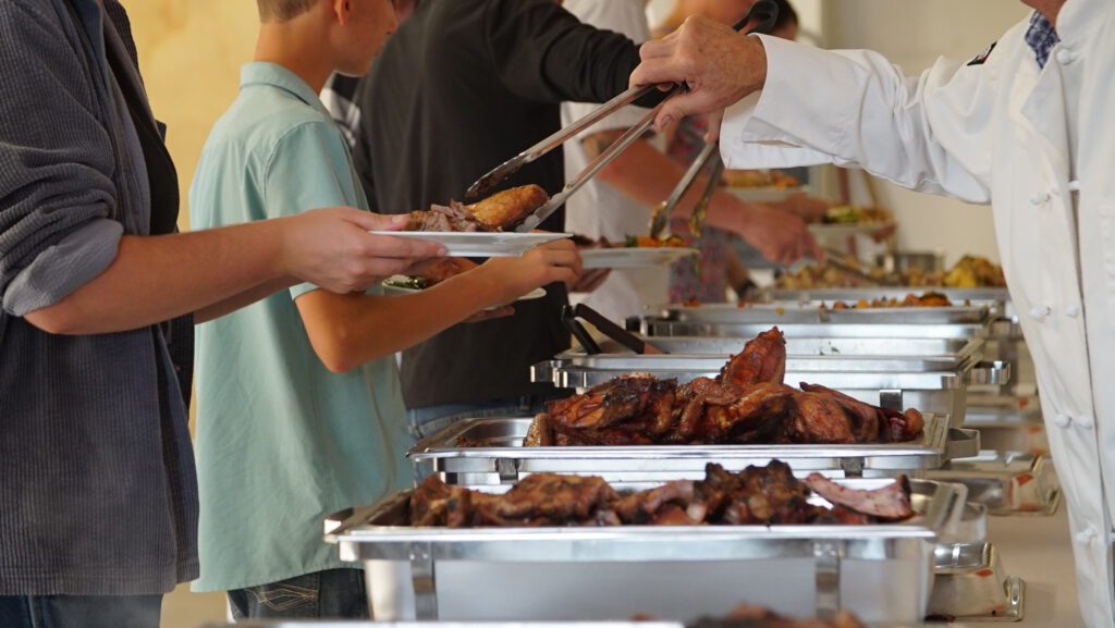 Guests serving themselves grilled meats from a buffet line at the Harvest on Main dinner