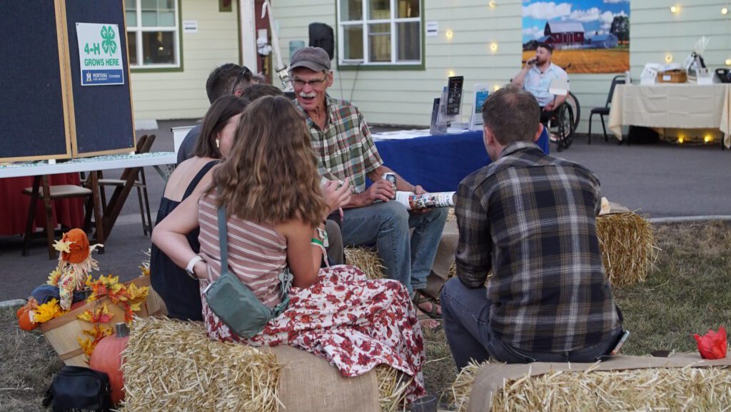 Guests gathered on hay bales with fall decor at the Harvest on Main evening event