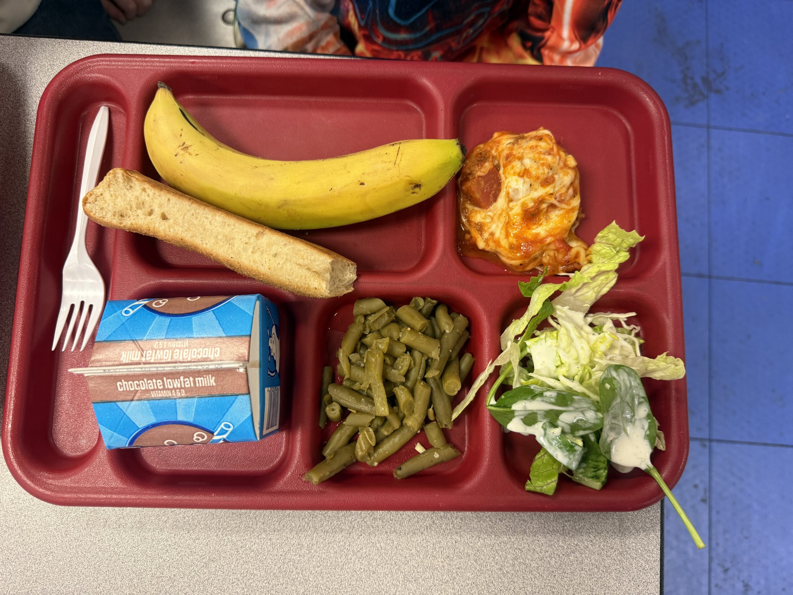 School lunch tray with Mission West marinara, a banana, a breadstick, green beans, salad, and chocolate milk
